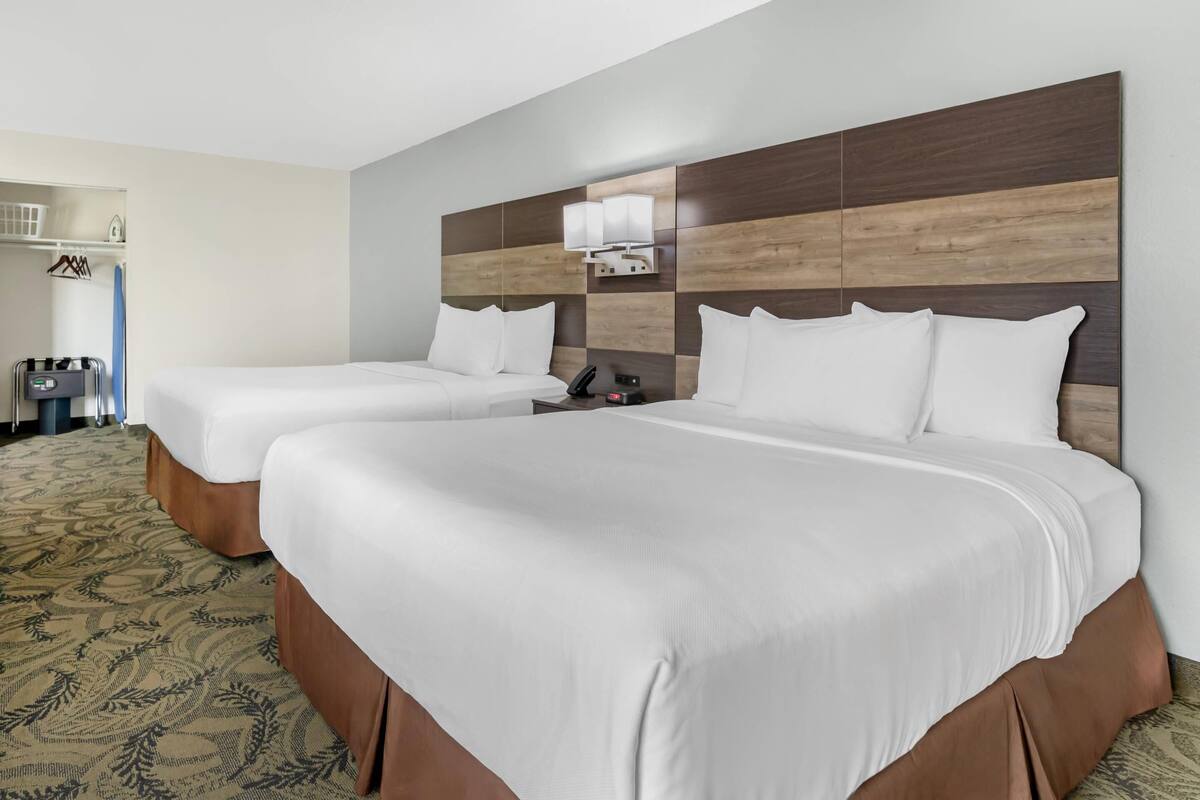 Une chambre d’hôtel avec deux lits, une tête de lit dotée d’un luminaire, un téléphone et une petite table.