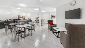 A modern kitchen with a dining area, a flat-screen TV, and a ceiling fan. - MainStay Suites Madison Airport (Madison)