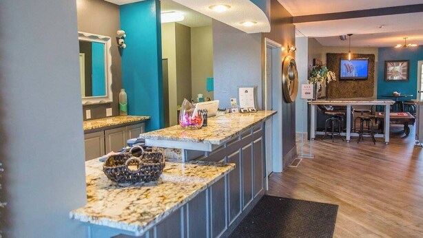 A modern kitchen with granite countertops, a built-in island, and a dining area with a bar. - River Hills Hotel (Mankato)