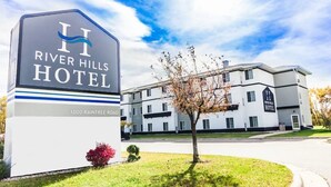 A River Hills Hotel sign with a modern building in the background. - River Hills Hotel (Mankato)