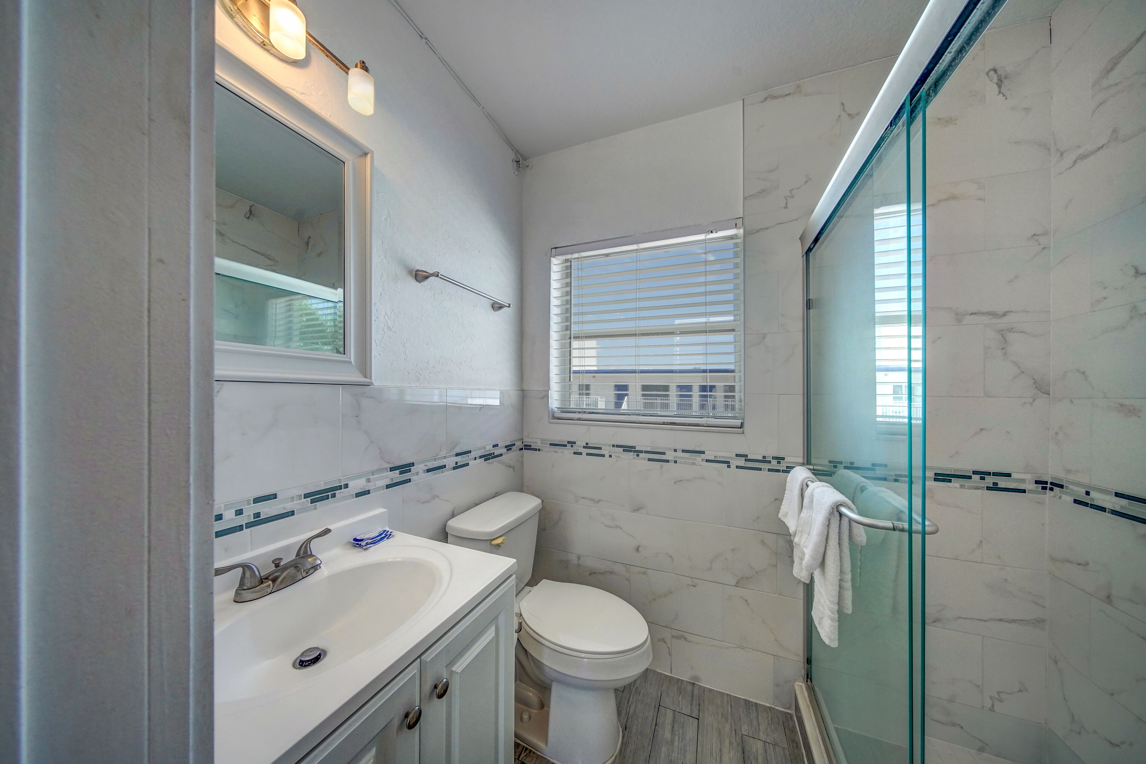 Une salle de bain avec un lavabo blanc, des toilettes et une cabine de douche en verre.