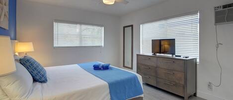 A bedroom with a bed, bedside lamp, dresser, and a ceiling fan.