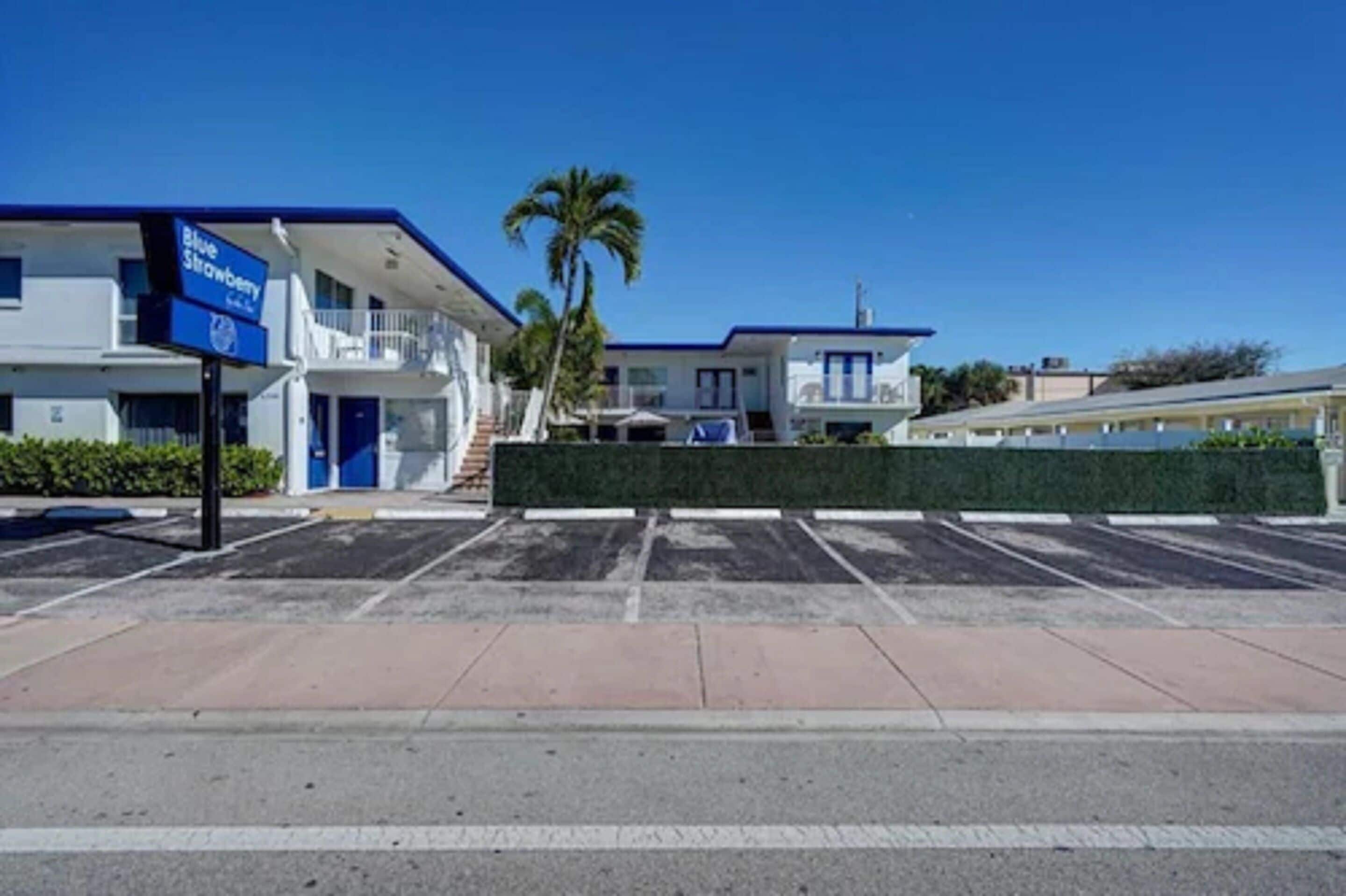 Ein Motel mit blauem Schild, einer Palme und einem Parkplatz.