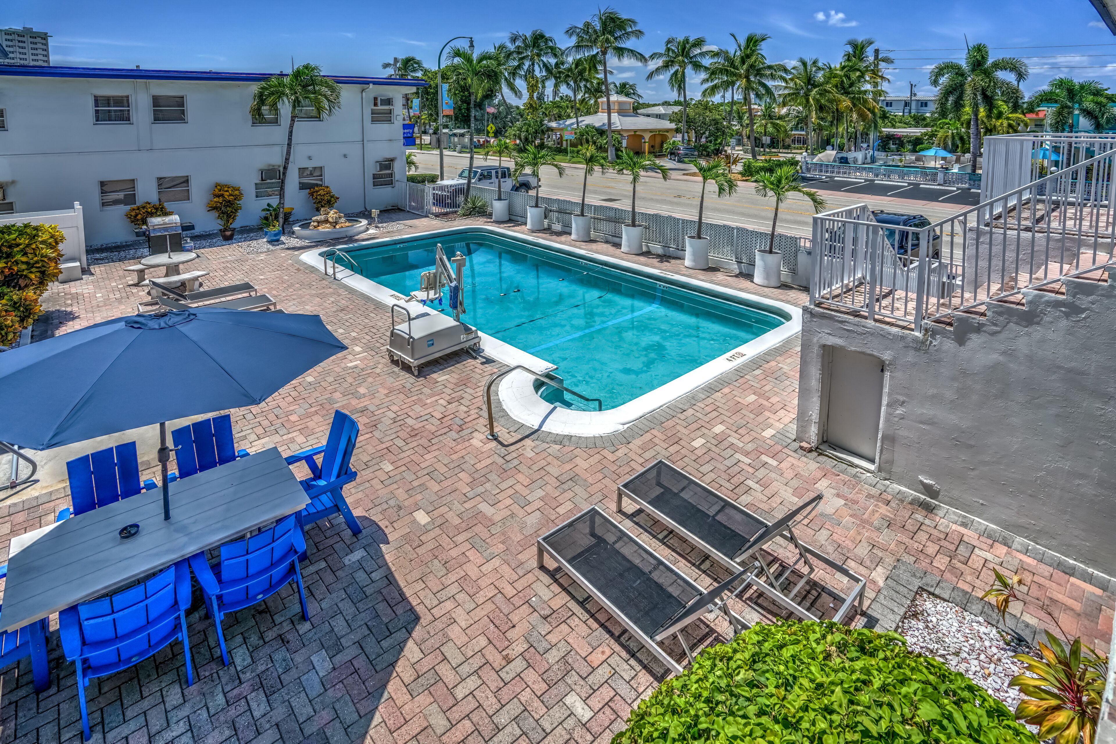 A rooftop pool area with a swimming pool, lounge chairs, and a table with umbrellas.