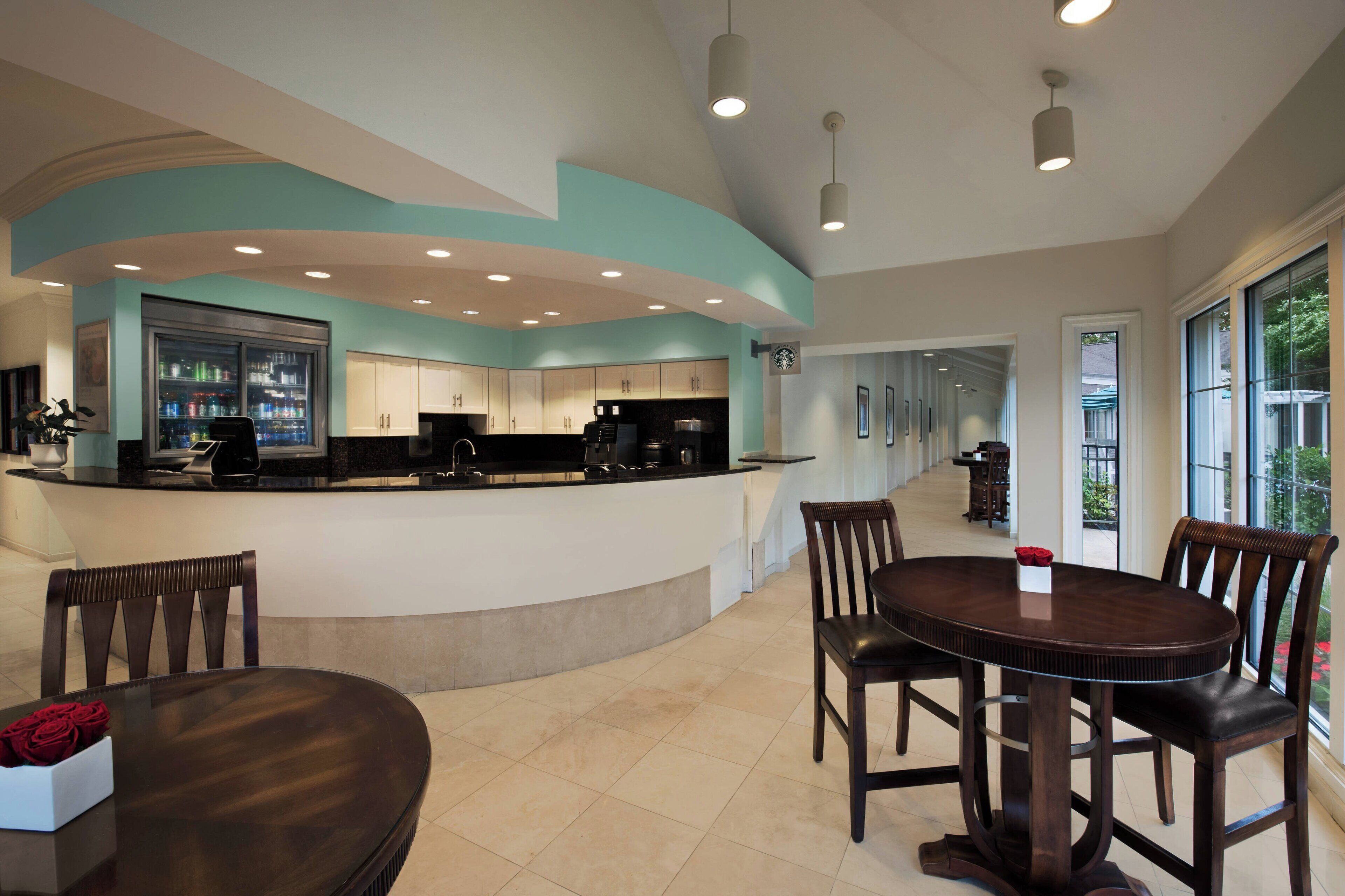 Una cocina moderna con una isla curva, un comedor con una mesa redonda y sillas, y vistas al exterior a través de grandes ventanales.