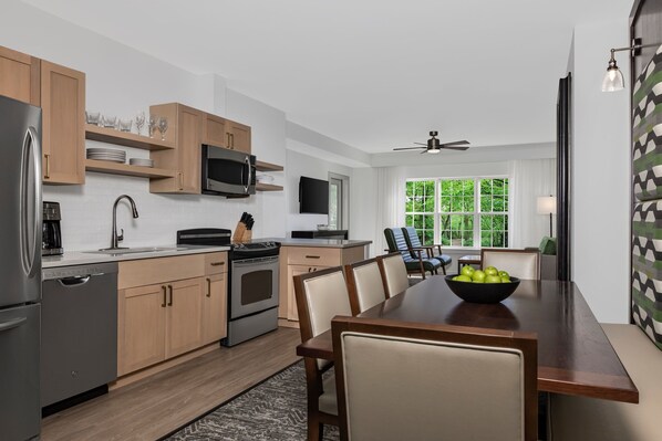 Una cocina moderna con armarios de madera, electrodomésticos de acero inoxidable y un comedor con mesa y sillas de madera.