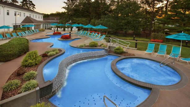 A multi-level pool with various seating areas and a building in the background.