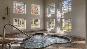 A spa area with a hot tub, large windows, and a view of trees.