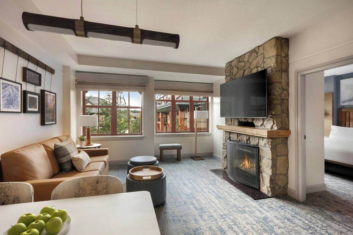A living room with a stone fireplace, a flat-screen TV, a sofa, and a dining table with apples.