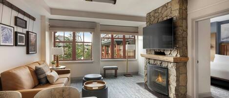 A living room with a stone fireplace, a flat-screen TV, a sofa, and a dining table with apples.