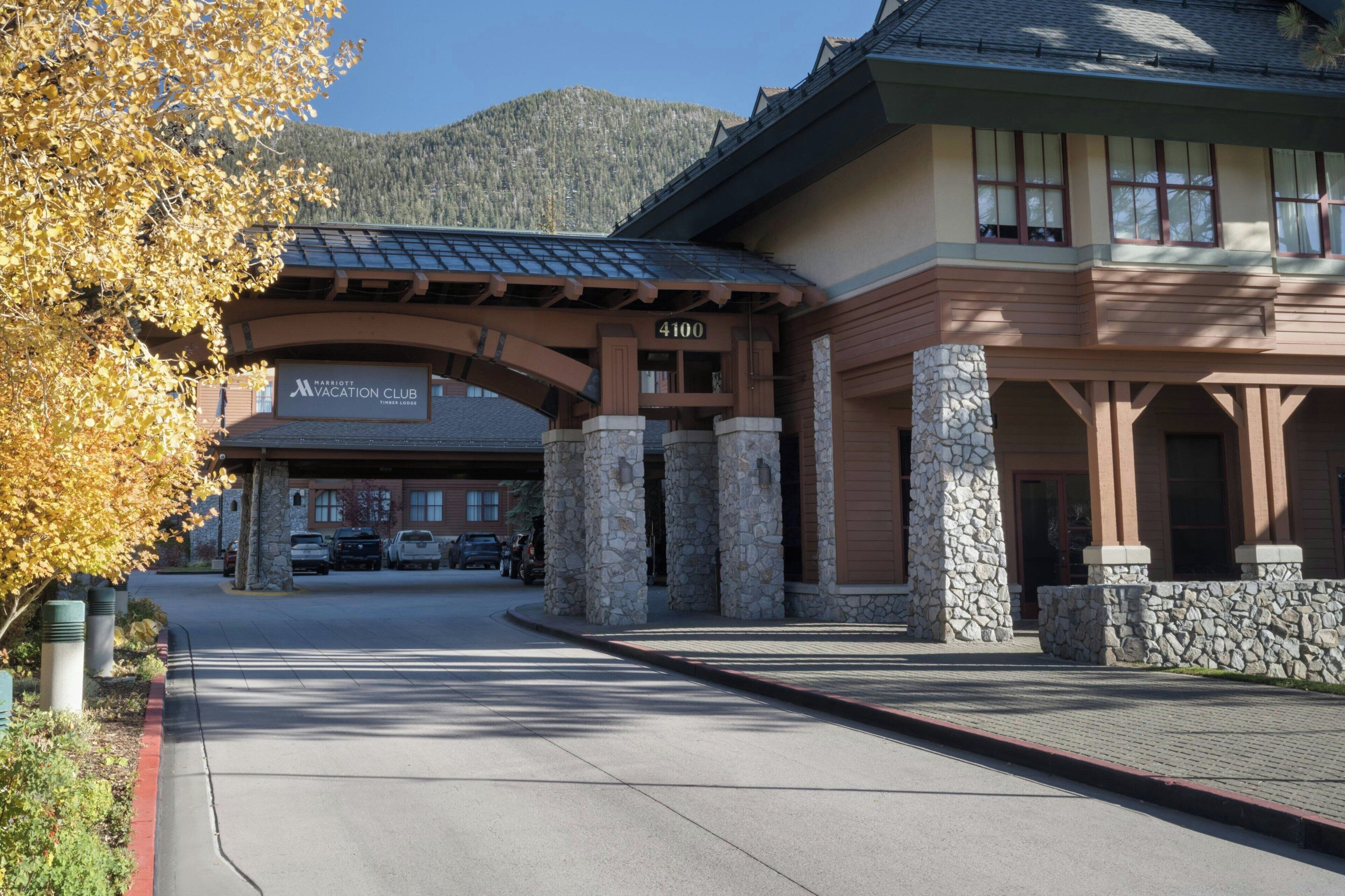 A building with a stone facade, a sign reading "Marriott Vacation Club," and a mountain backdrop.