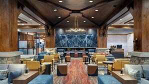 A modern lobby with a stone fireplace, comfortable seating, and a large chandelier. - Marriott's Timber Lodge (South Lake Tahoe)