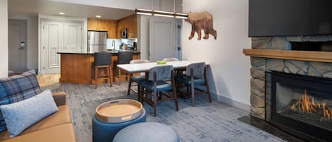 Una sala de estar moderna con chimenea, un comedor con sillas y una cocina al fondo.