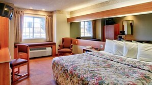 A hotel room with a bed, a desk, a chair, a TV, and a window. - Western Skies Inn And Suites (Los Lunas)