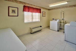 A laundry room with a washing machine, dryer, and stacked laundry baskets. - Western Skies Inn And Suites (Los Lunas)
