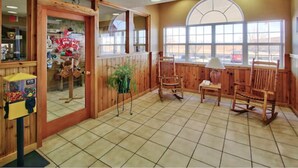A room with wooden walls, a large window, and a seating area with chairs. - Western Skies Inn And Suites (Los Lunas)