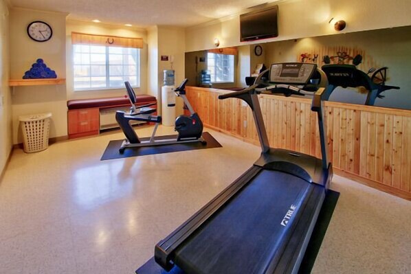 A gym with treadmills, a bench, and a water cooler. - Western Skies Inn And Suites (Los Lunas)