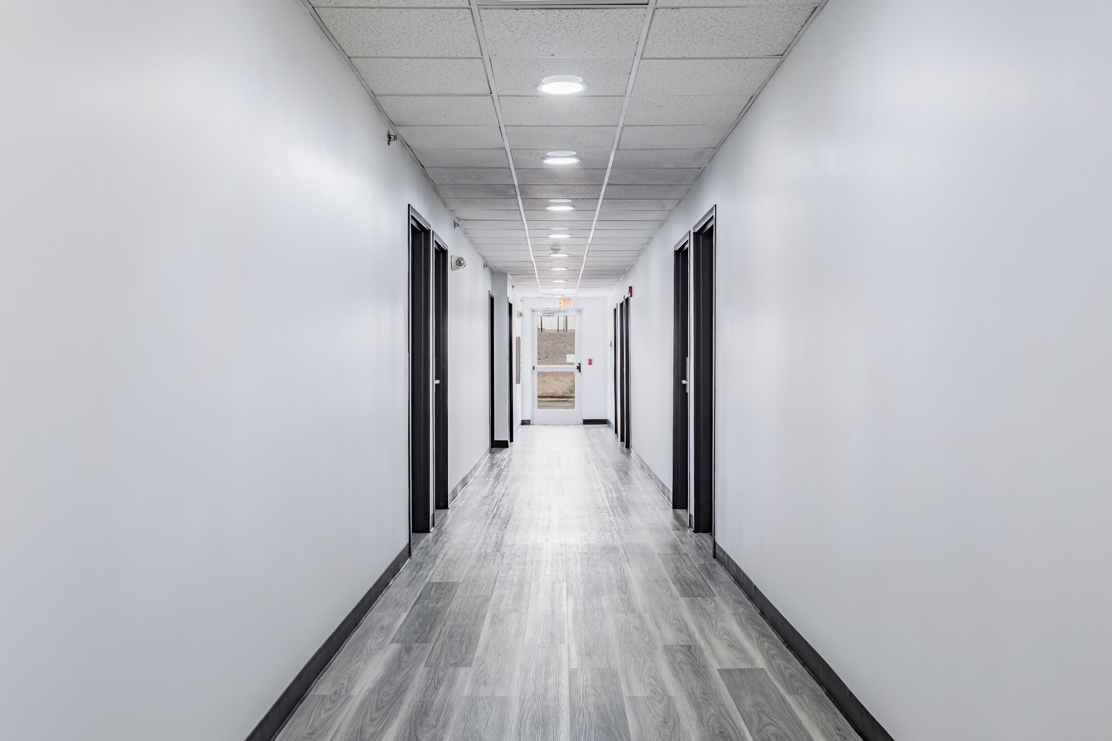 A long, narrow hallway with a tiled ceiling and a wooden floor.