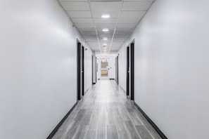 A long, narrow hallway with a tiled ceiling and a wooden floor. - Western Skies Inn And Suites (Los Lunas)