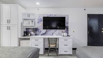 Ein modernes Schlafzimmer mit Schreibtisch, zwei Betten, einem Fernseher und einem Kleiderschrank.