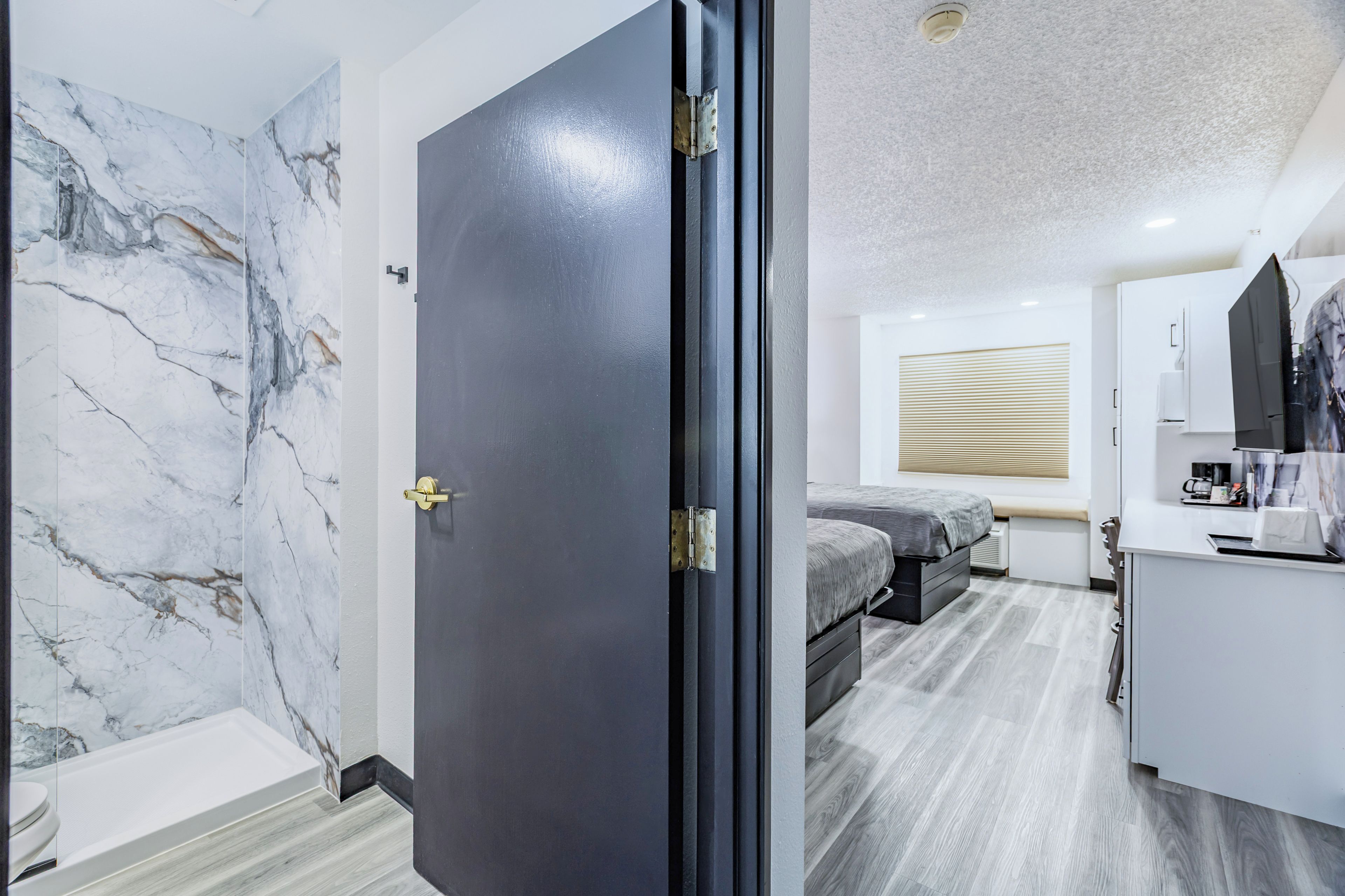 Un dormitorio moderno con pared de mármol, una cama, un escritorio y un baño con bañera.
