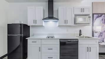Una cocina moderna con armarios blancos, un refrigerador negro, un lavavajillas de acero inoxidable y un microondas.