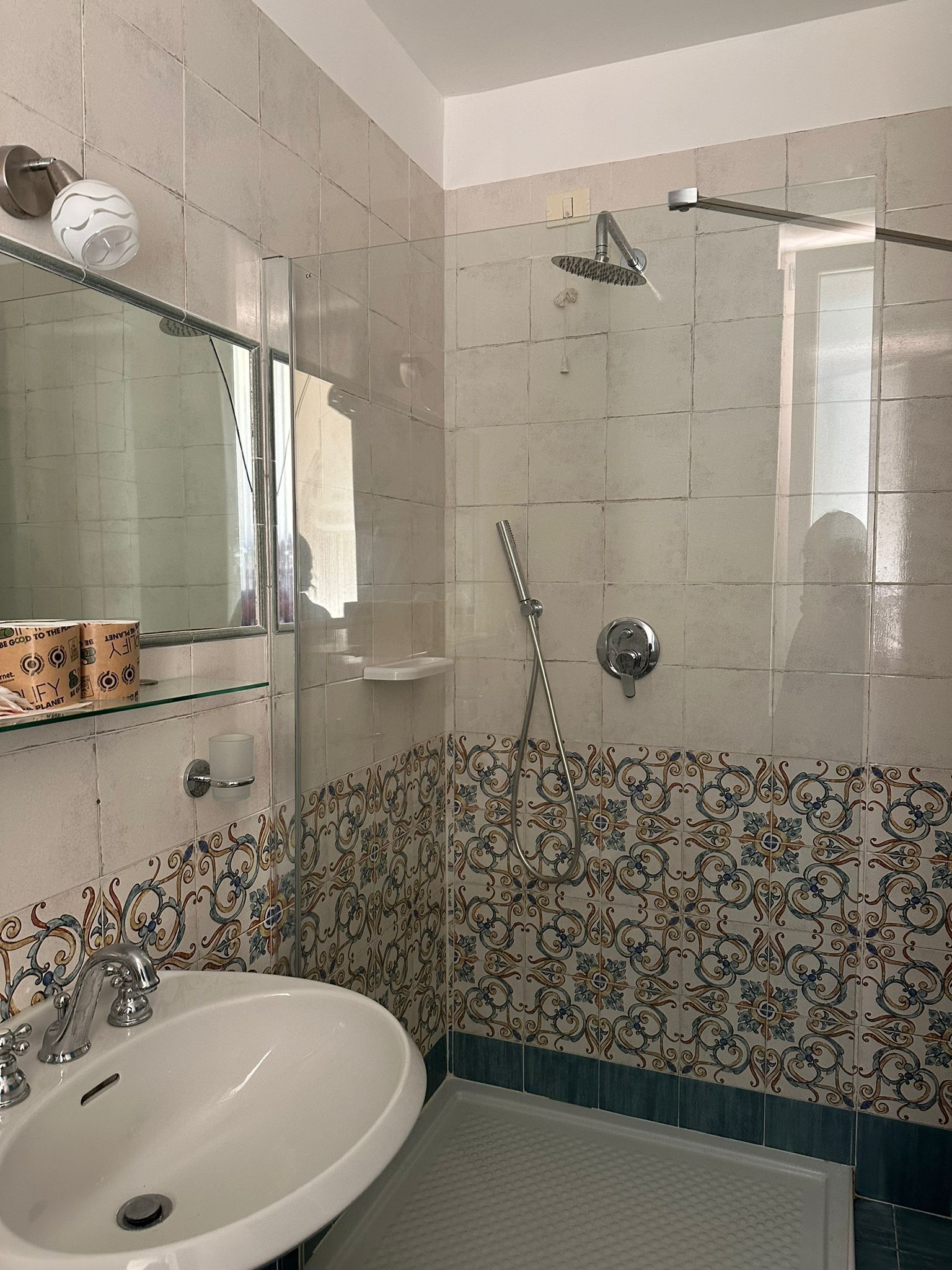 A bathroom with a sink, mirror, shower, and decorative tiles.