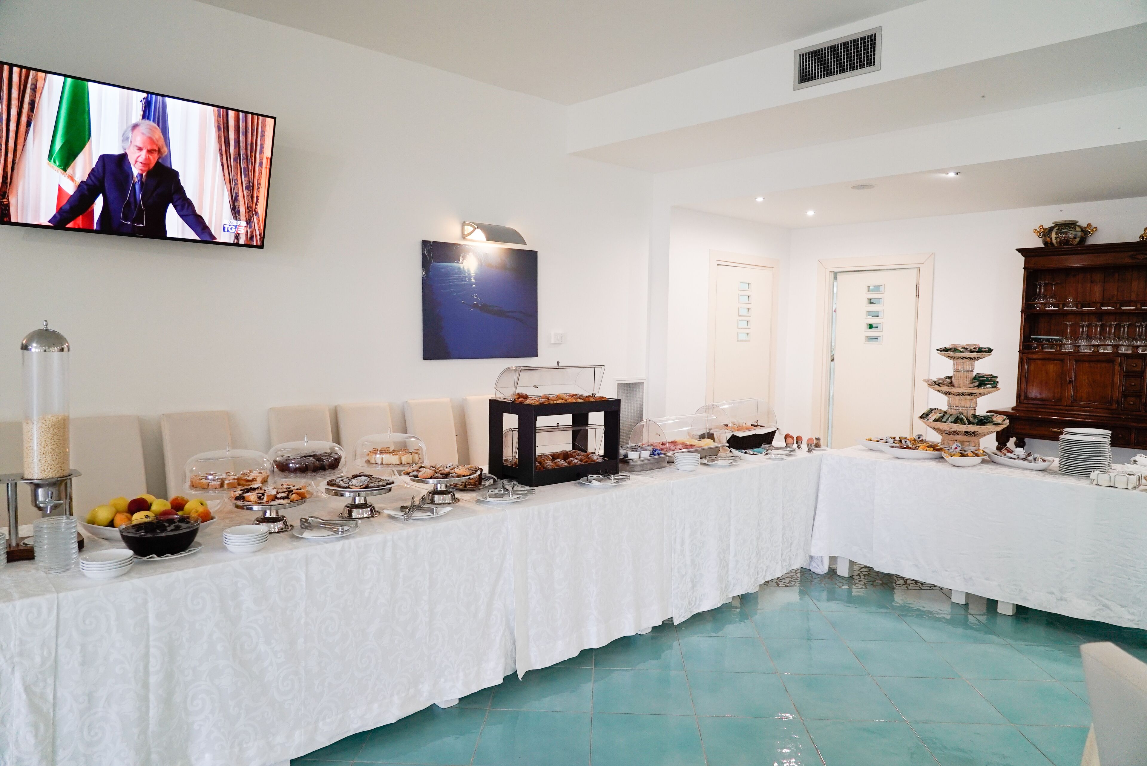 Un buffet proposant une variété de plats et un écran de télévision sur lequel est diffusée l’image d’une personne.