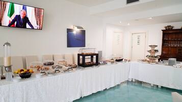 Un buffet proposant une variété de plats et un écran de télévision sur lequel est diffusée l’image d’une personne.