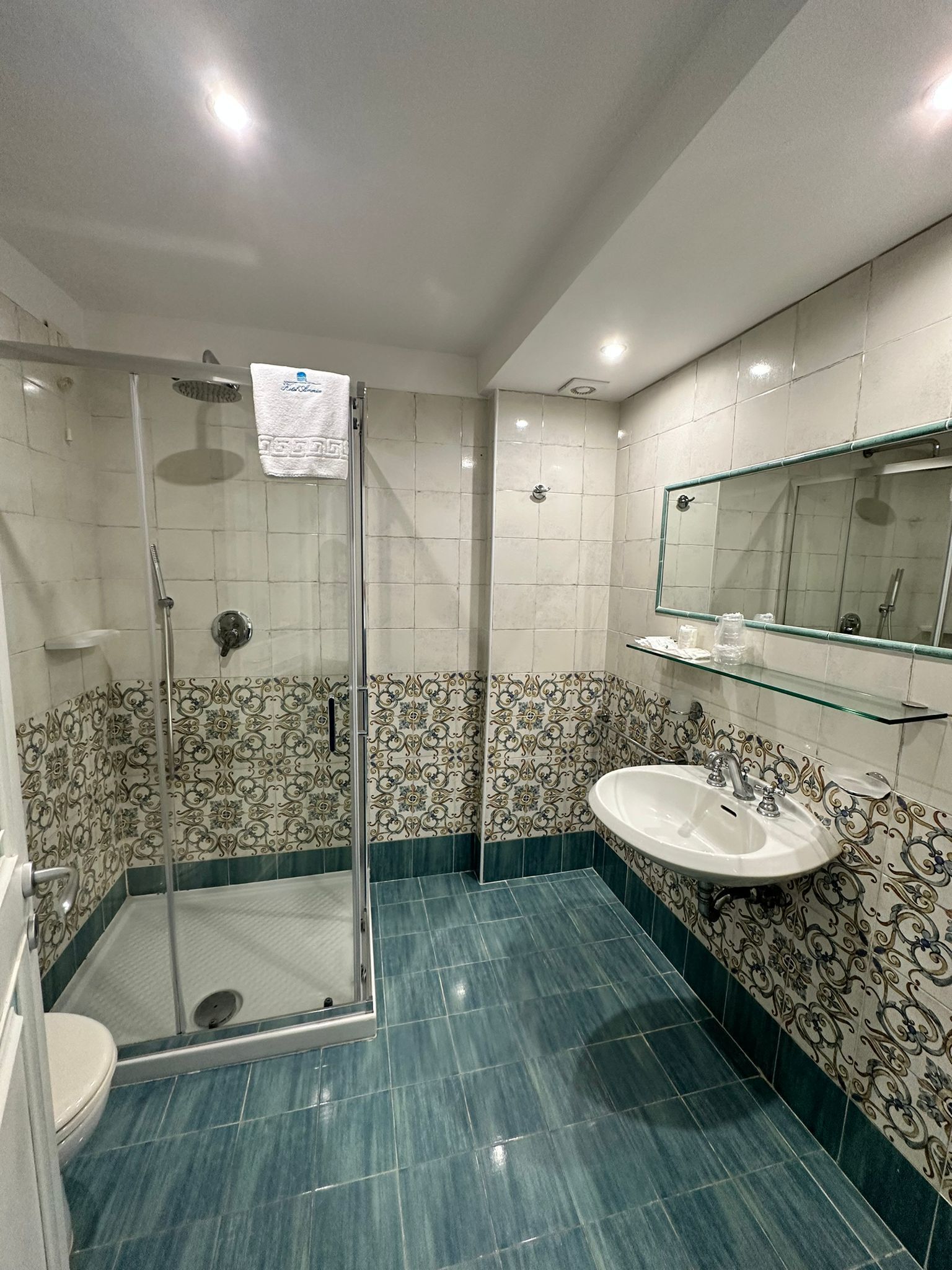 Ein Badezimmer mit Dusche, Toilette, Waschbecken und Spiegel.