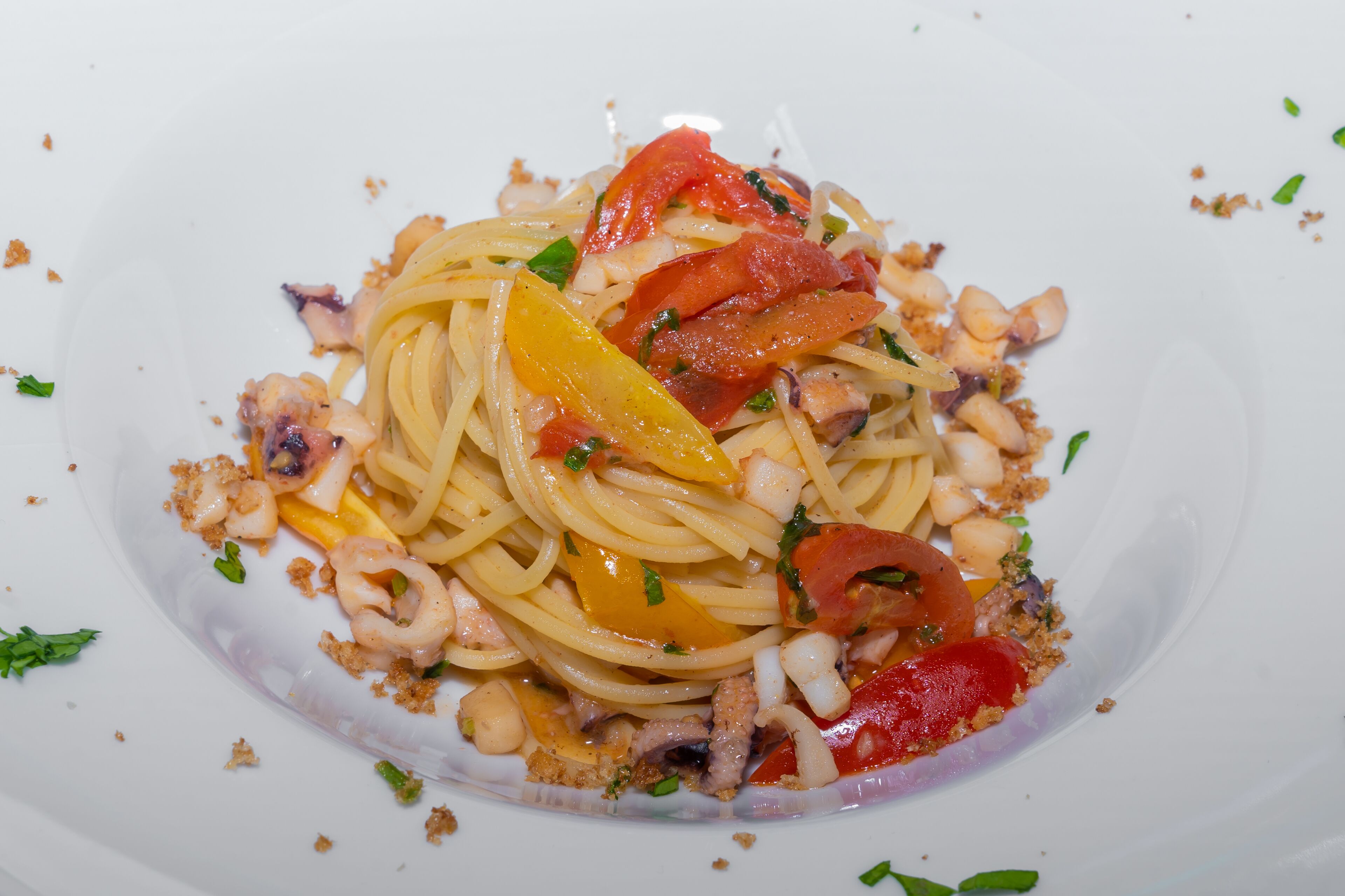 Un piatto di spaghetti con pomodoro, basilico e frutti di mare.