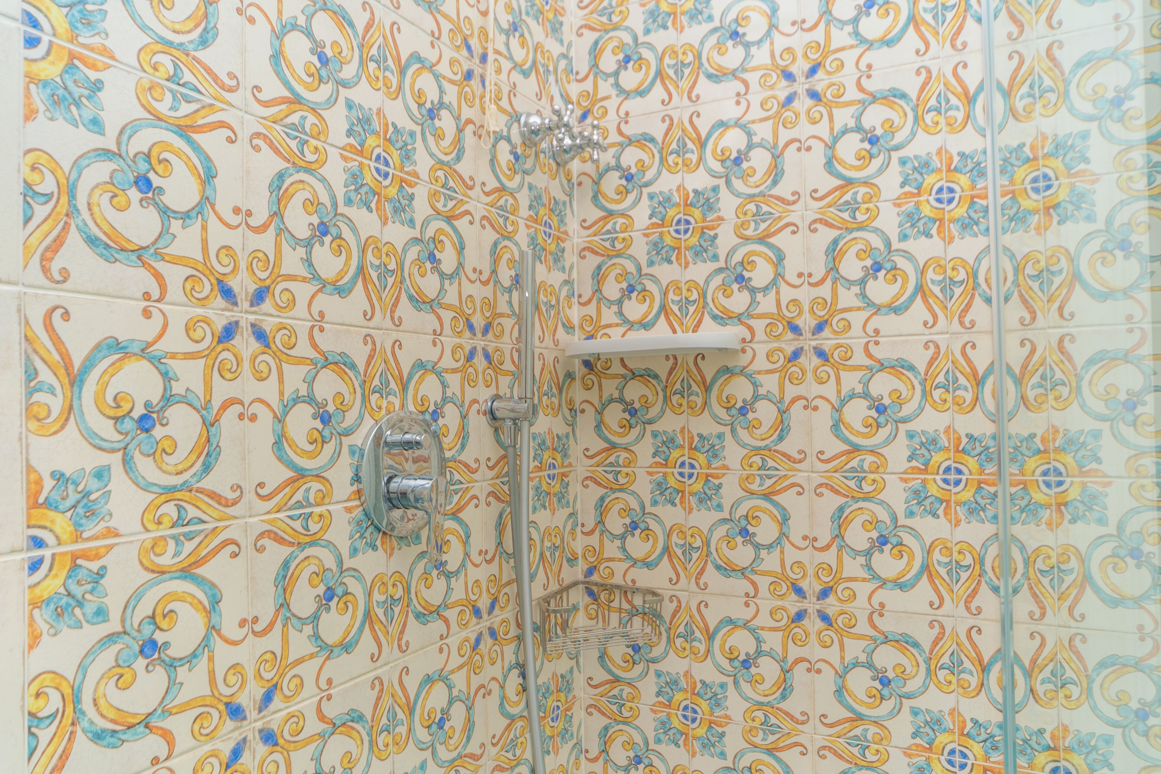 A bathroom with ornate tile patterns and a shower area.
