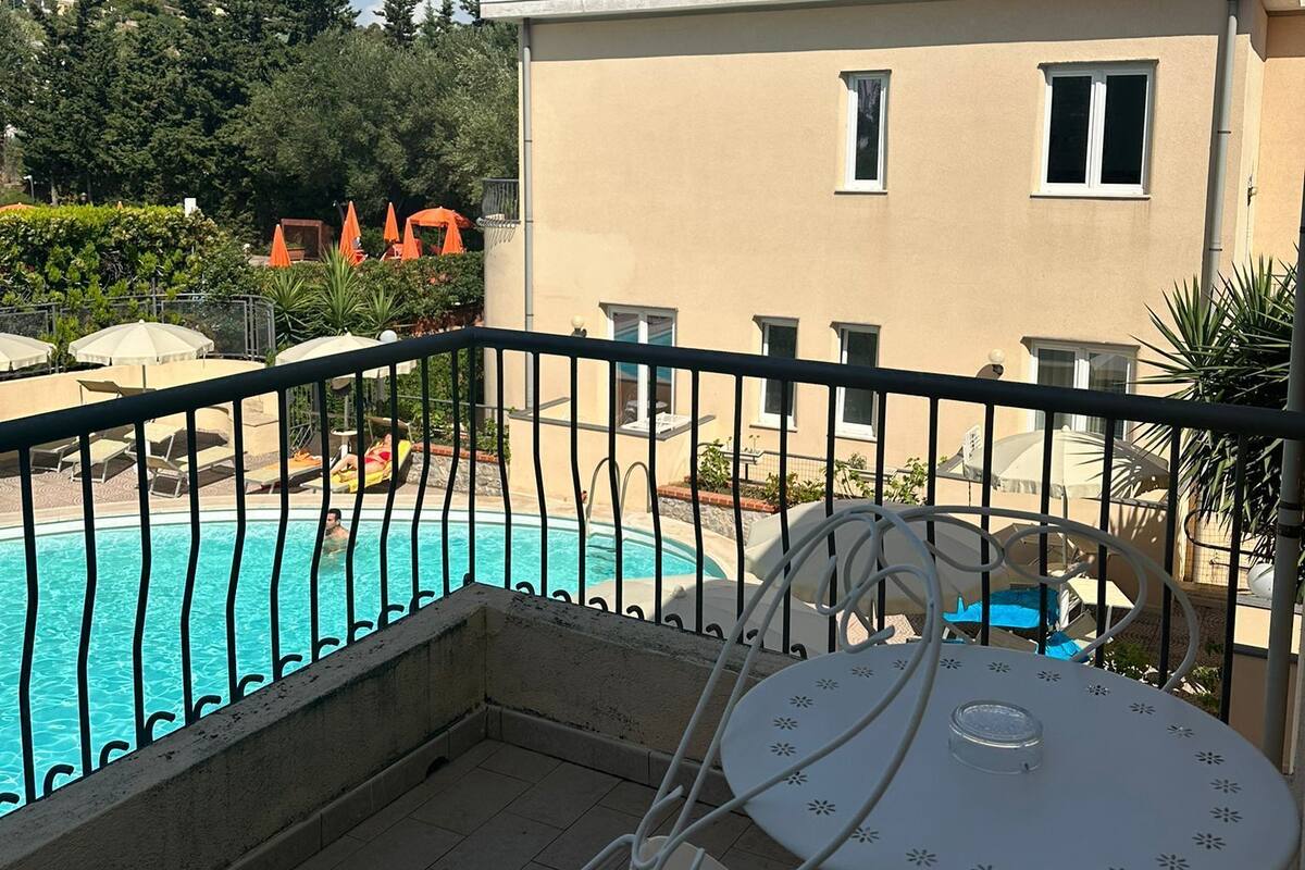 A balcony with a pool, a table, and chairs.