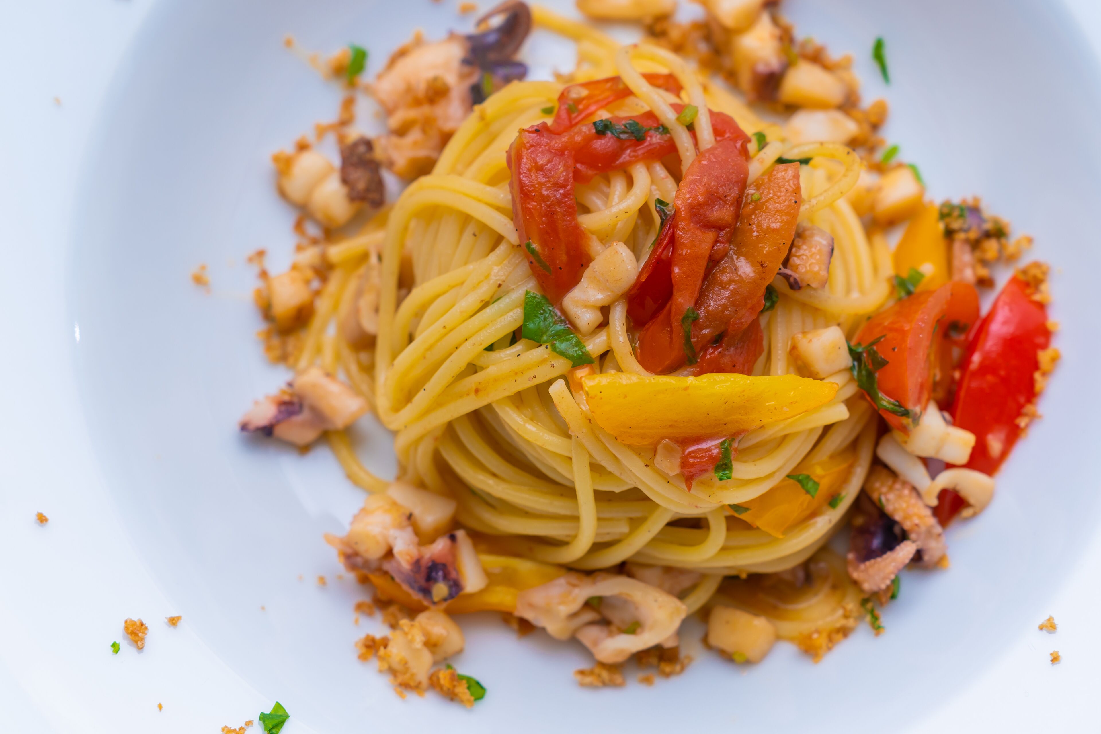 A plate of spaghetti with tomatoes, cheese, and herbs.