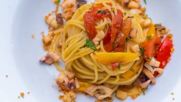 A plate of spaghetti with tomatoes, cheese, and herbs.
