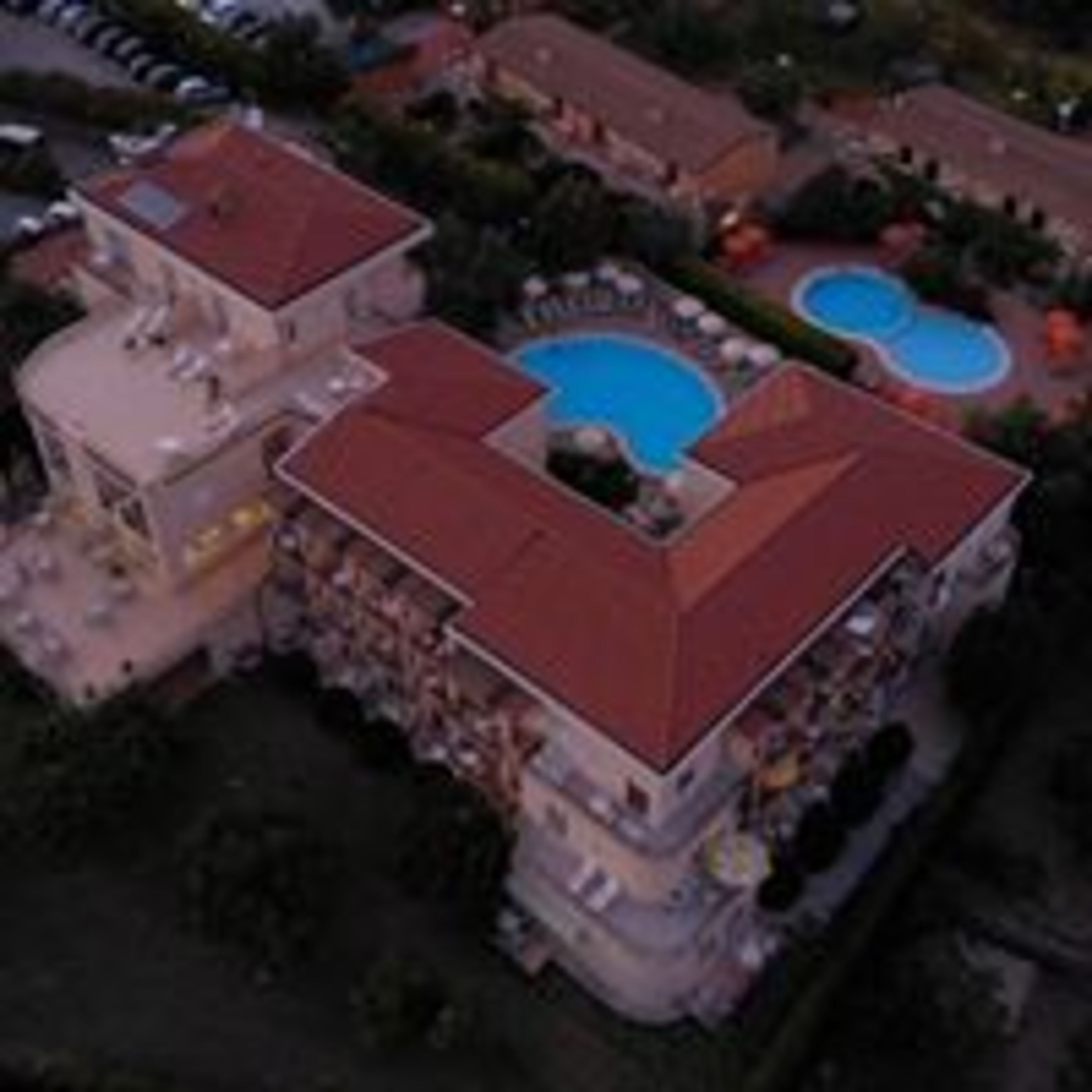Un edificio a più piani con tetto rosso, piscina e area verde curata.
