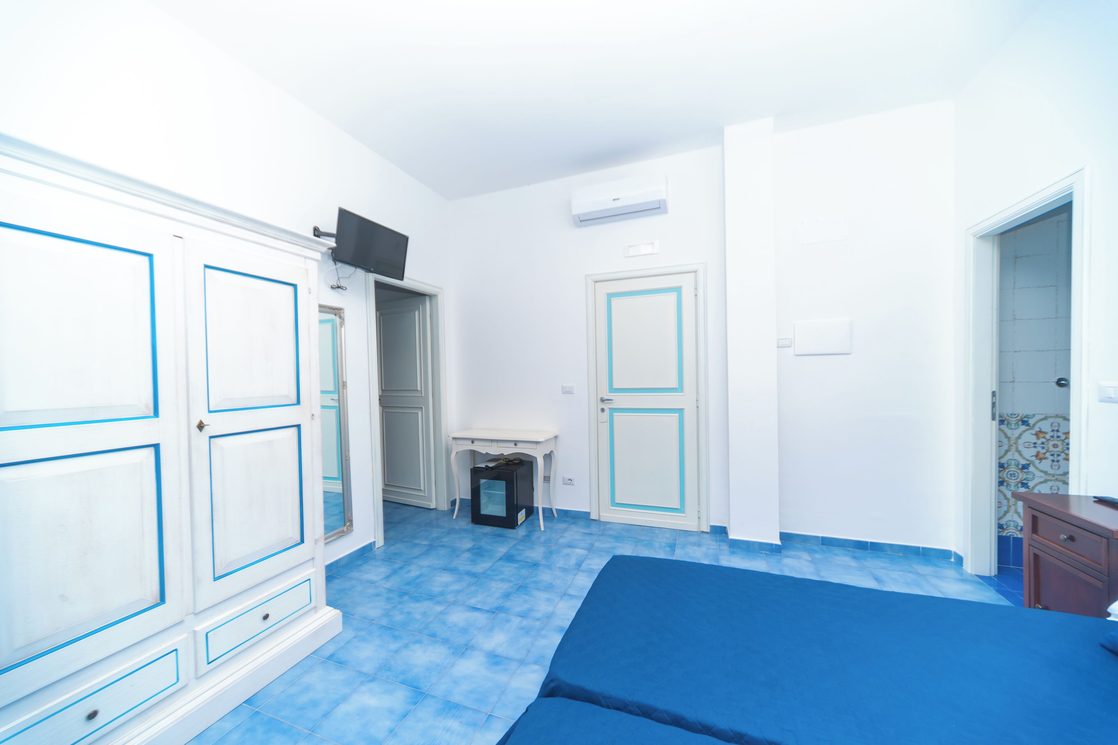 Una habitación con cama, escritorio y televisor.