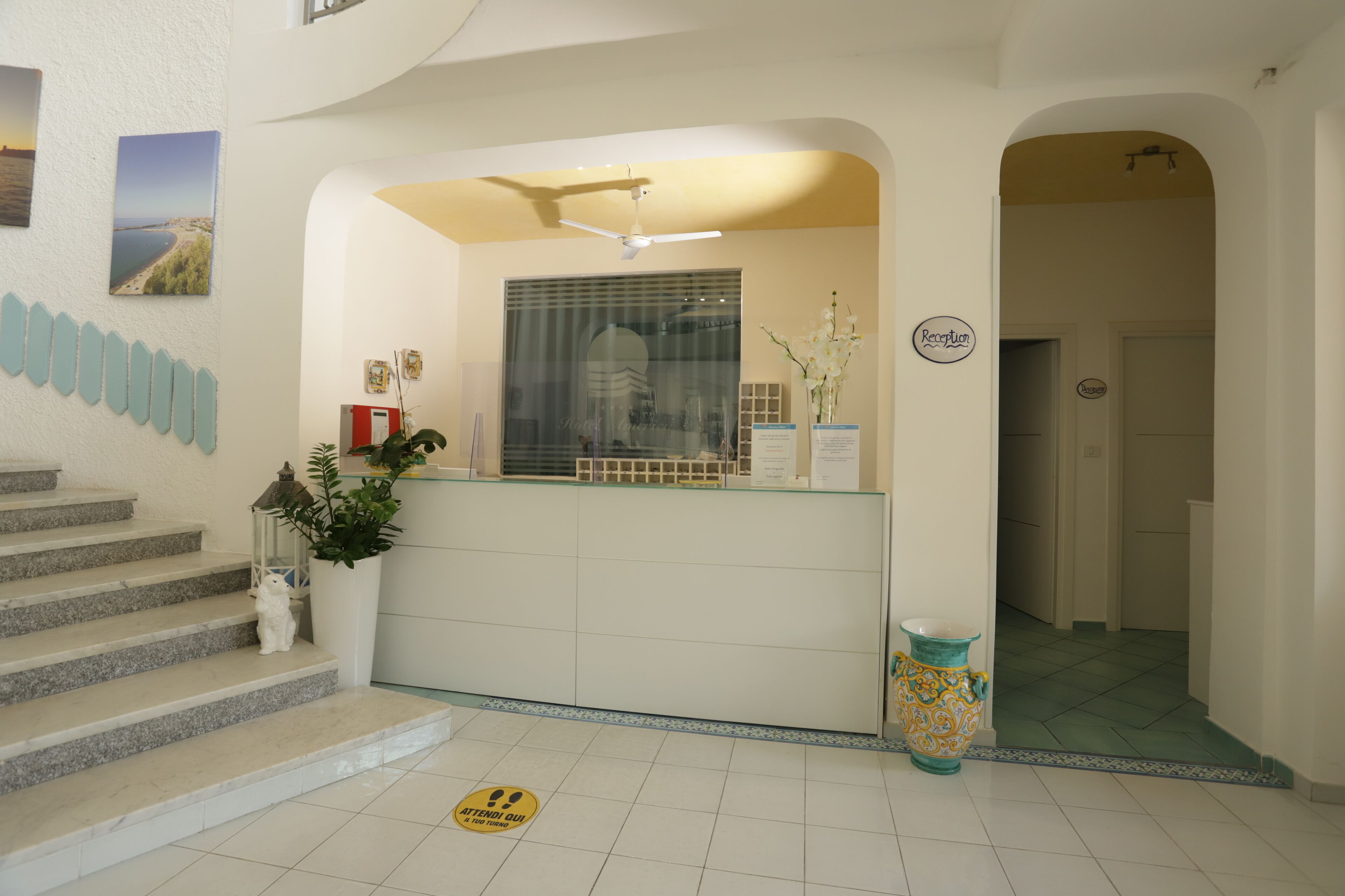 A reception area with a reception desk, a staircase, and a large window.