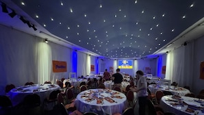A conference room with round tables, white curtains, and ceiling lights. - Cristal Palace Hotel (Buenos Aires)
