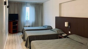 A hotel room with two single beds, a TV, a bedside table with a lamp, and a window with curtains. - Cristal Palace Hotel (Buenos Aires)