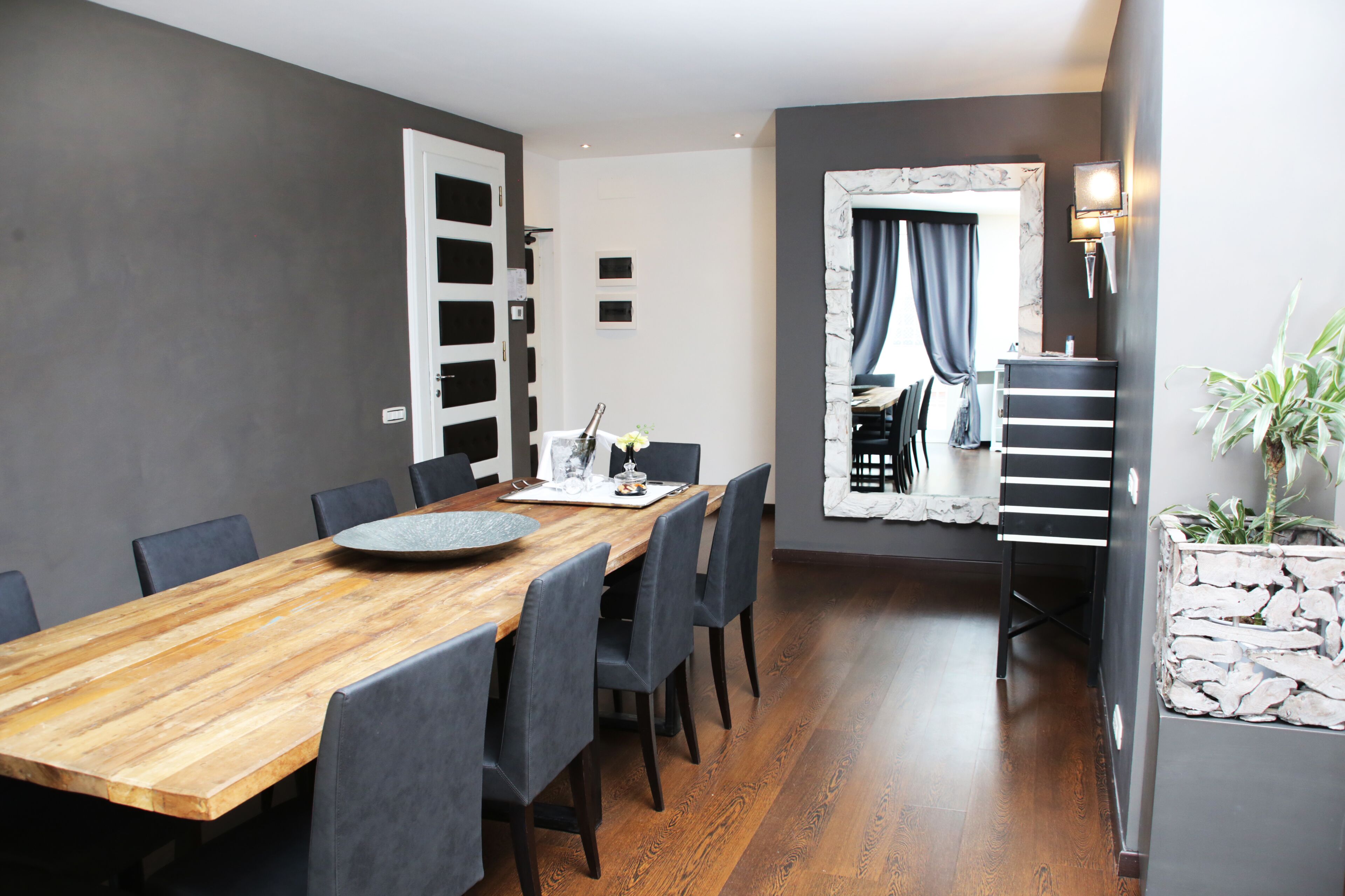 A modern dining area with a wooden table, grey chairs, and a stone accent wall.