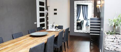 A modern dining area with a wooden table, grey chairs, and a stone accent wall.