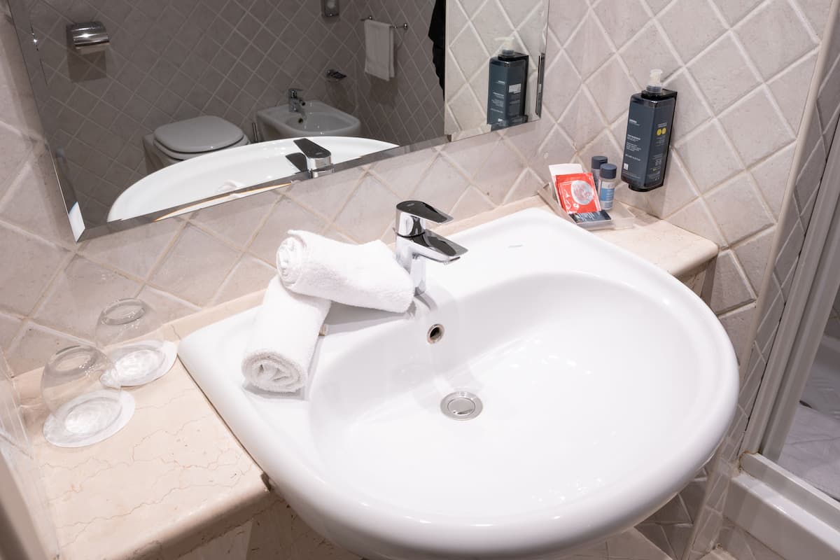 Uma casa de banho com uma pia branca, um espelho e artigos de higiene no balcão.