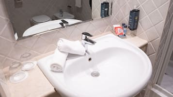 A bathroom with a white sink, a mirror, and toiletries on the countertop.