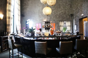 Eine Bar mit einer Theke, Barhocker und dekorativer Beleuchtung.