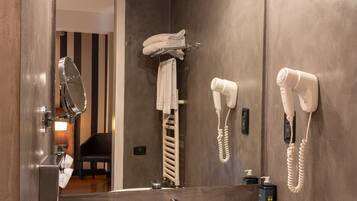Un bagno con un ampio specchio, un lavandino e due asciugacapelli montati a parete.