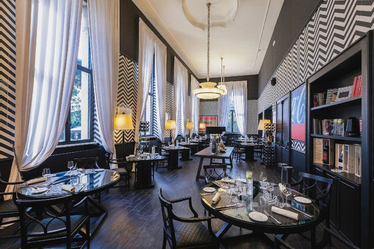 Un restaurante con varias mesas, sillas y lámparas colgantes.
