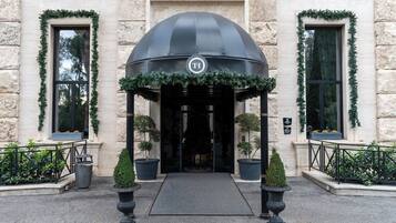 A hotel entrance with a black canopy, potted plants, and a stone facade.