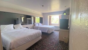 A hotel room with two beds, a large window, a flat-screen TV, and a patterned carpet. - Motel 6 McAlester, OK - South (McAlester)
