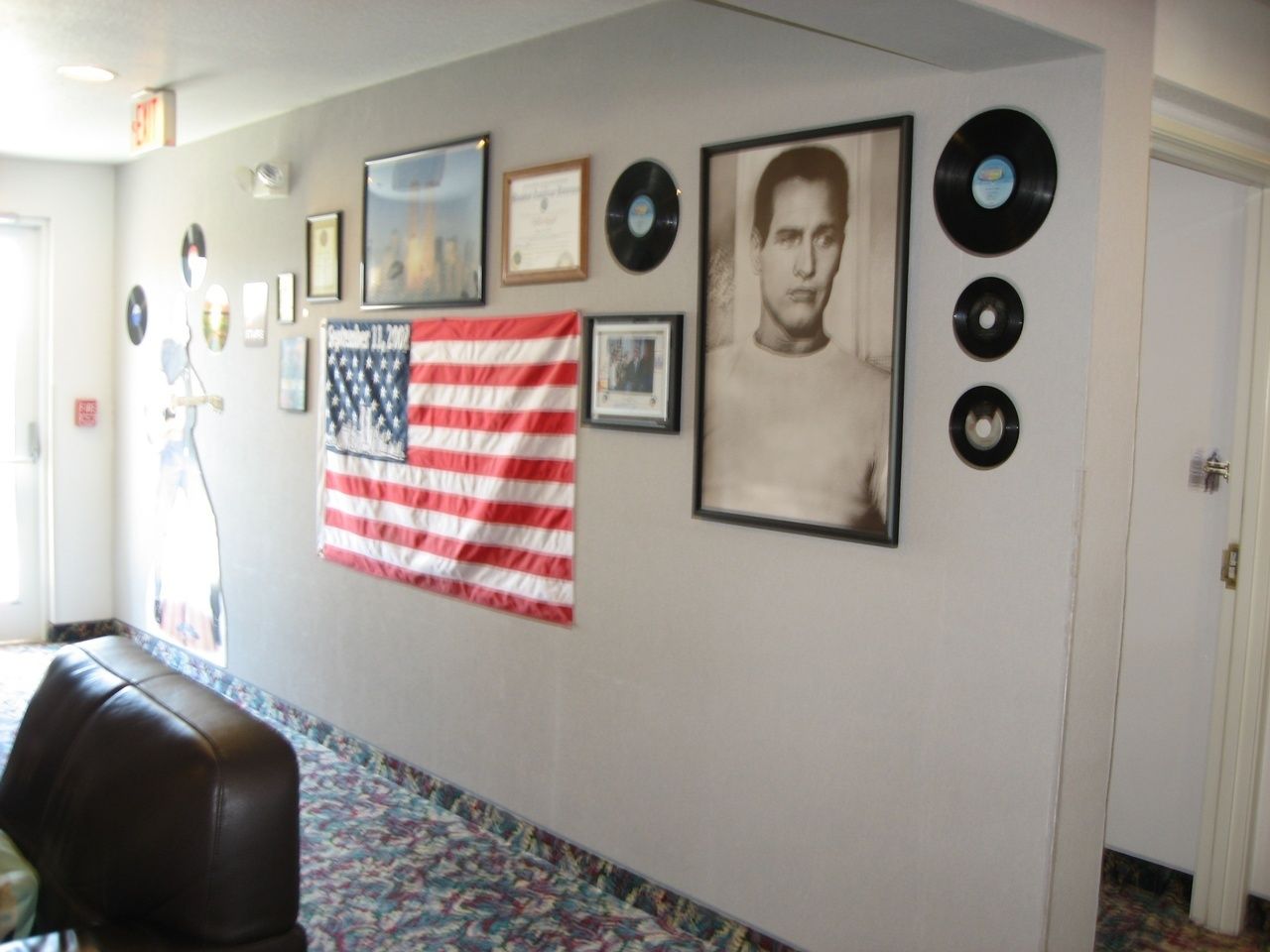 Un couloir orné d’un drapeau américain, de photos encadrées et de disques vinyle accrochés au mur.